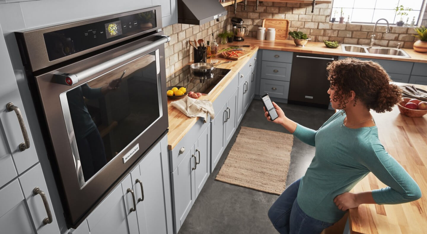 Person controlling smart appliance settings through app on phone