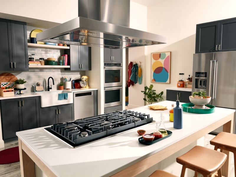 Suite of KitchenAid® stainless steel appliances, including a gas cooktop and island canopy range hood