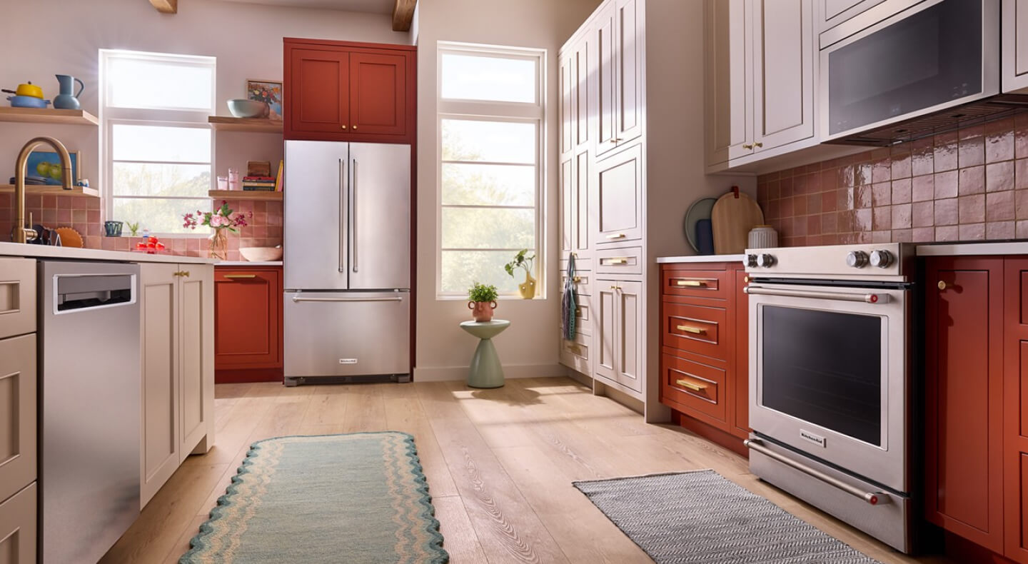 Suite of KitchenAid® stainless steel appliances in vibrant orange cabinetry