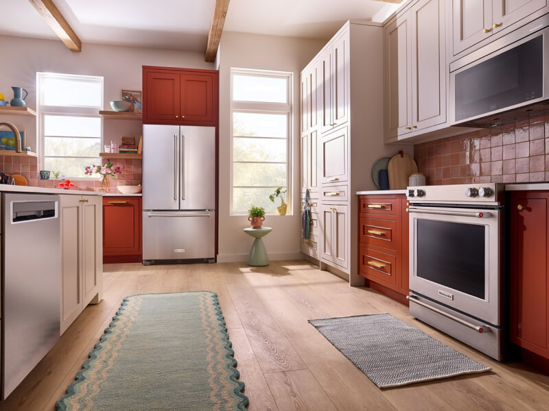 Suite of KitchenAid® stainless steel appliances in vibrant orange cabinetry
