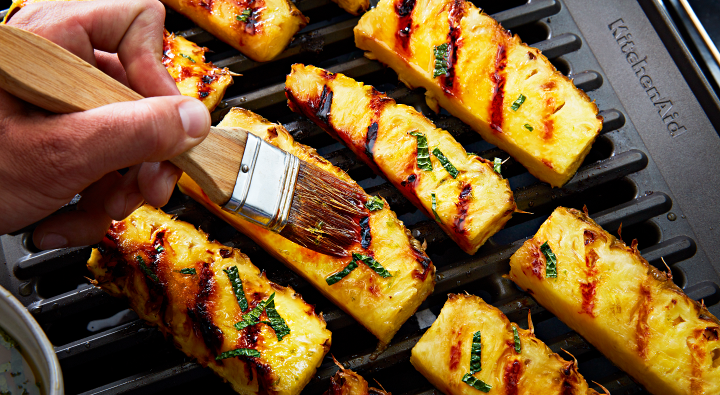 Hand dressing grilled pineapples with a pastry brush Hand dressing grilled pineapples with a pastry brush