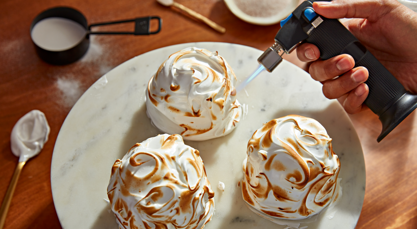 Hand using a culinary torch to caramelize ganache Hand using a culinary torch to caramelize ganache