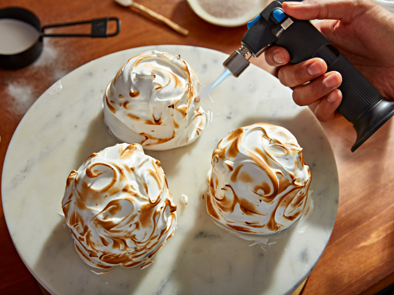 Hand using a culinary torch to caramelize ganache Hand using a culinary torch to caramelize ganache