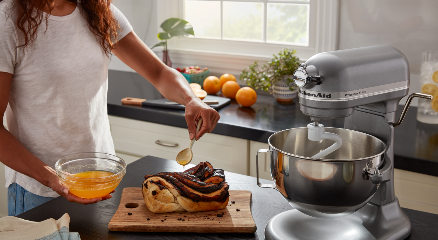 Person drizzling melted ingredients onto homemade bread Person drizzling melted ingredients onto homemade bread