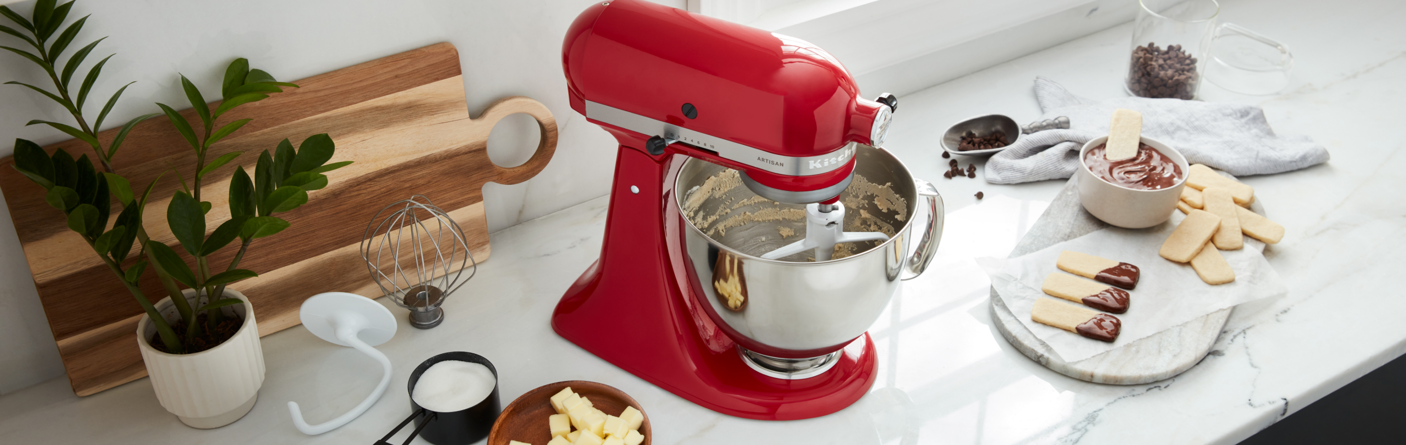 KitchenAid® Stand Mixer on a countertop surrounded by various sweet ingredients
