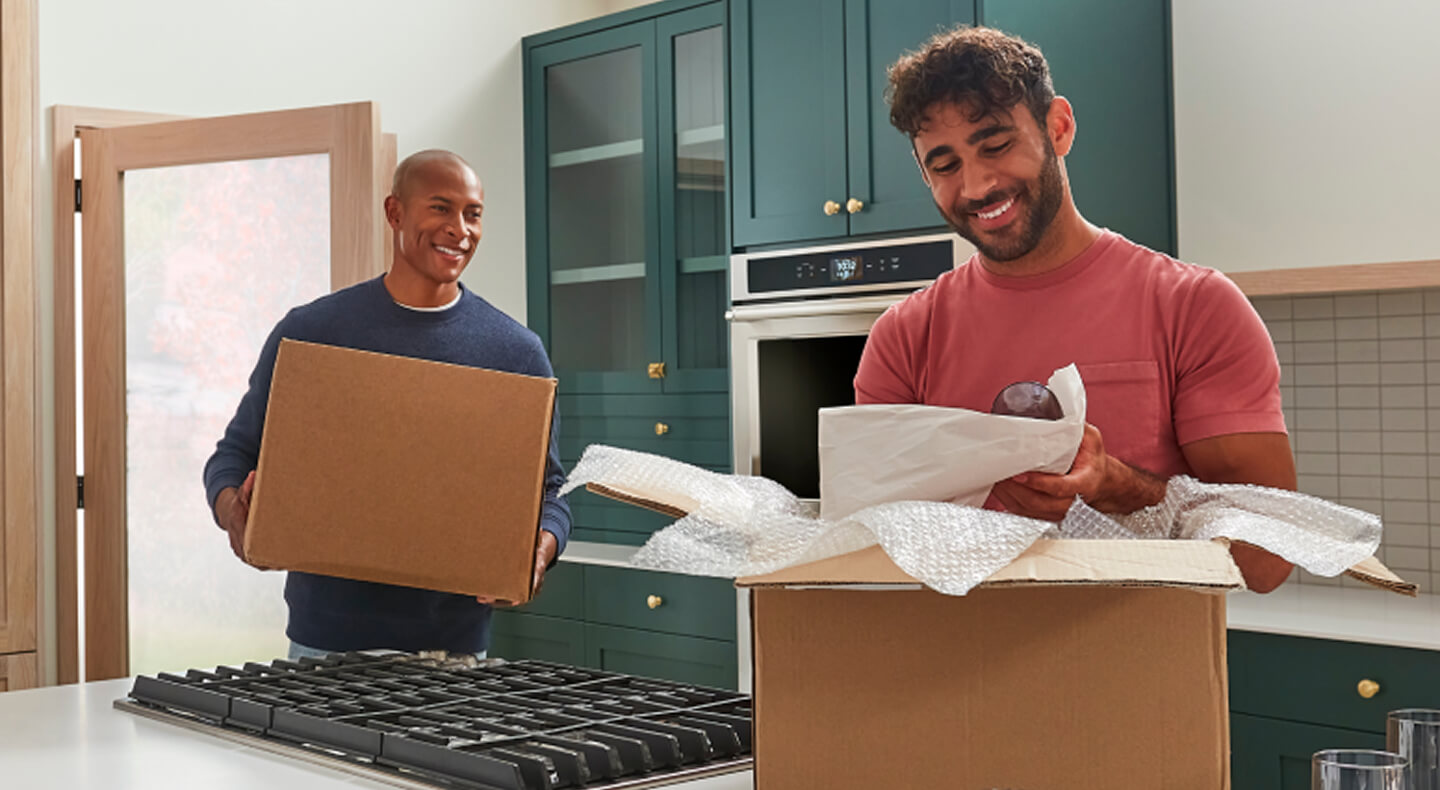 Two men moving and unpacking boxes in a remodeled kitchen Two men moving and unpacking boxes in a remodeled kitchen