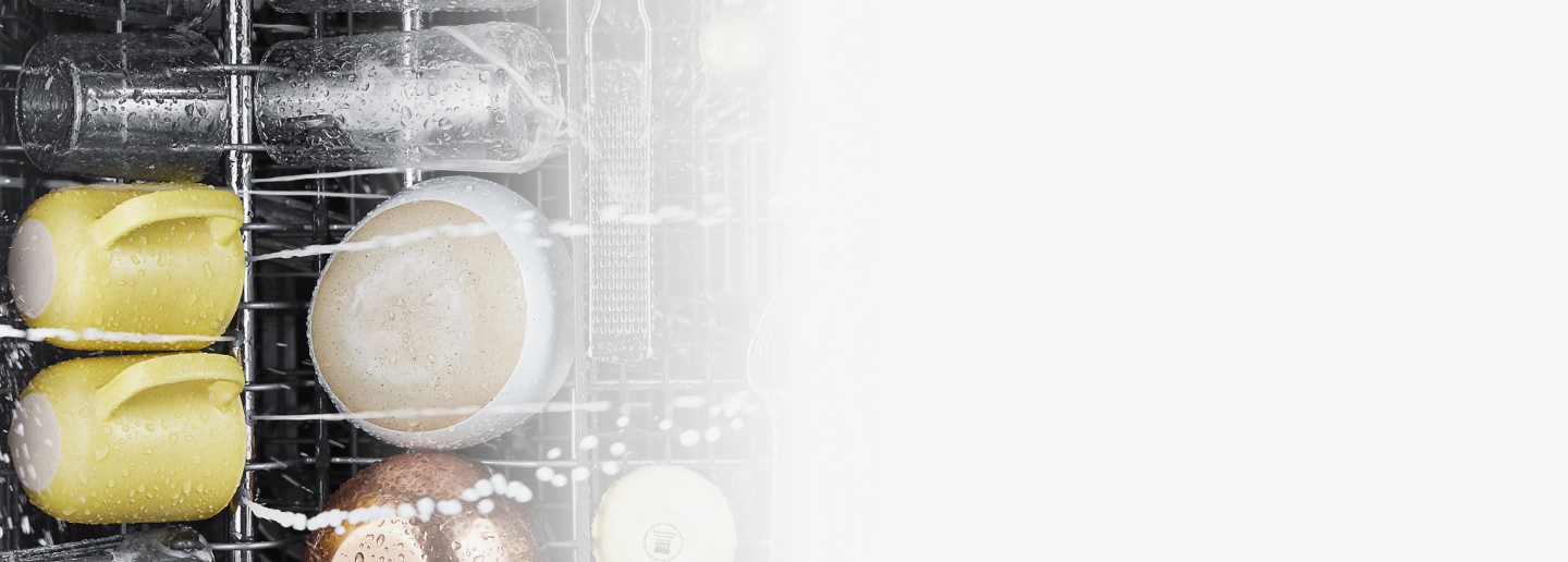 Mugs and bowls being washed inside a dishwasher