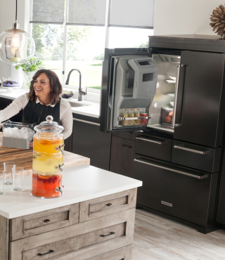Person smiling at a kitchen island with an open refrigerator in the background