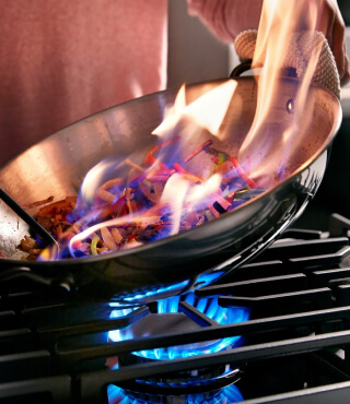 Person cooking in a wok on a gas range
