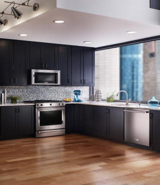 An open kitchen layout with dark cabinets and stainless steel appliances