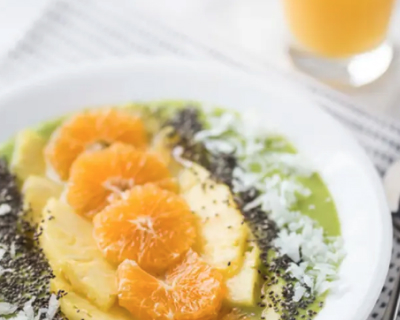 Tropical smoothie bowl topped with oranges, pineapple and shredded coconut