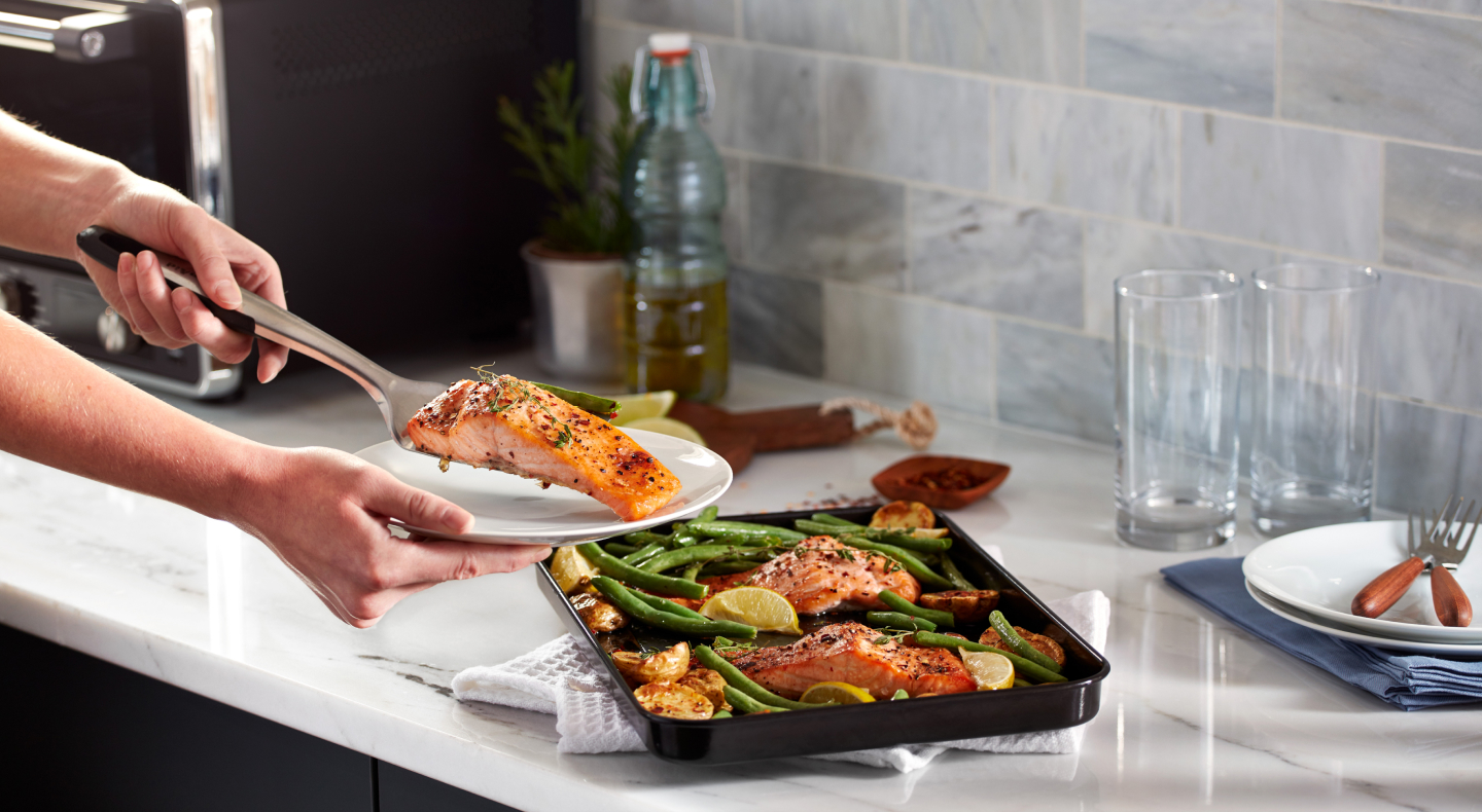 Person placing salmon filet on a plate Person placing salmon filet on a plate