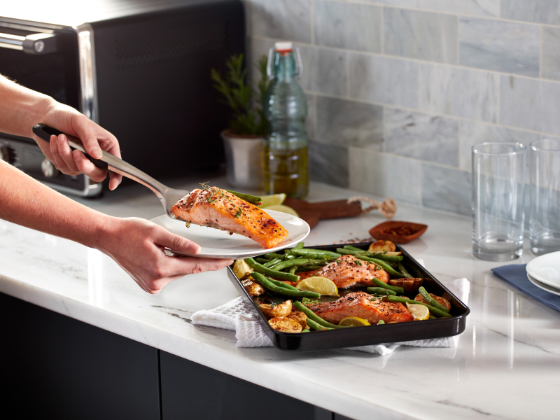 Person placing salmon filet on a plate Person placing salmon filet on a plate