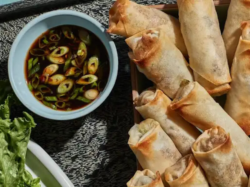 Pork and shrimp spring rolls on platter by dipping sauce Pork and shrimp spring rolls on platter by dipping sauce