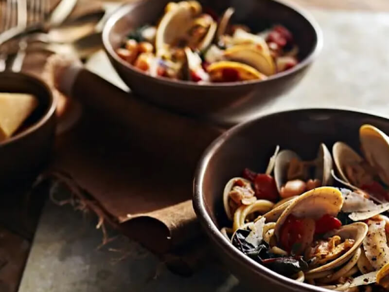 Bowls of steamed clams with beans and greens