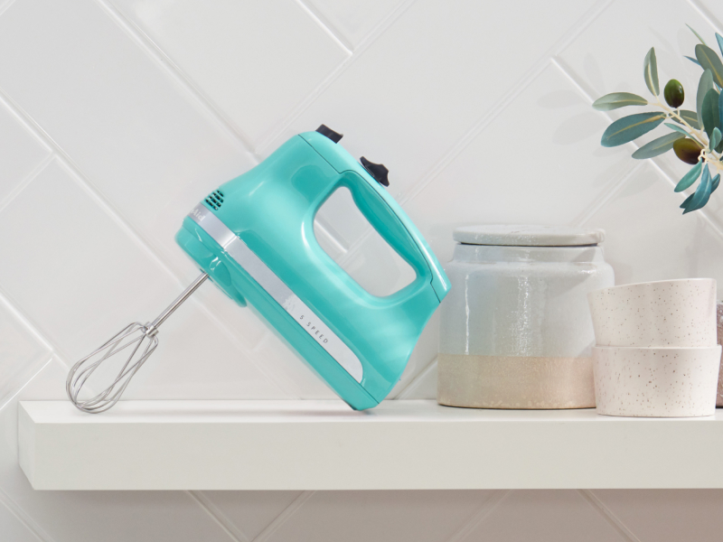 A teal KitchenAid® hand mixer on a modern kitchen counter. A teal KitchenAid® hand mixer on a modern kitchen counter.