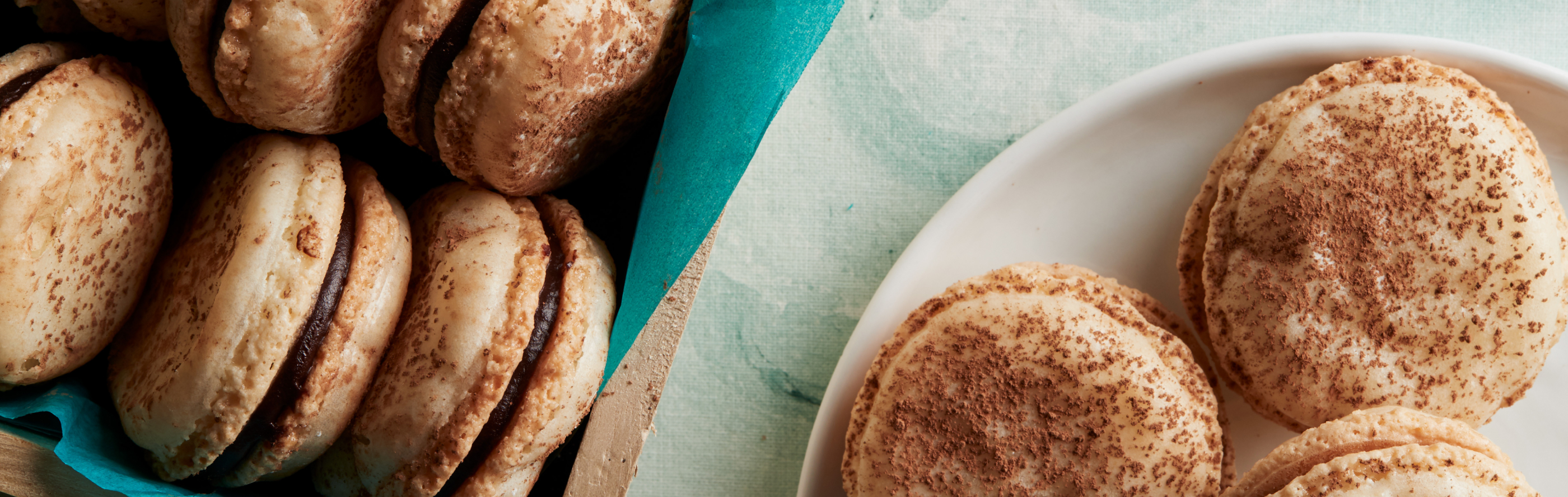 Almond macarons with dark chocolate ganache filling on a plate.
