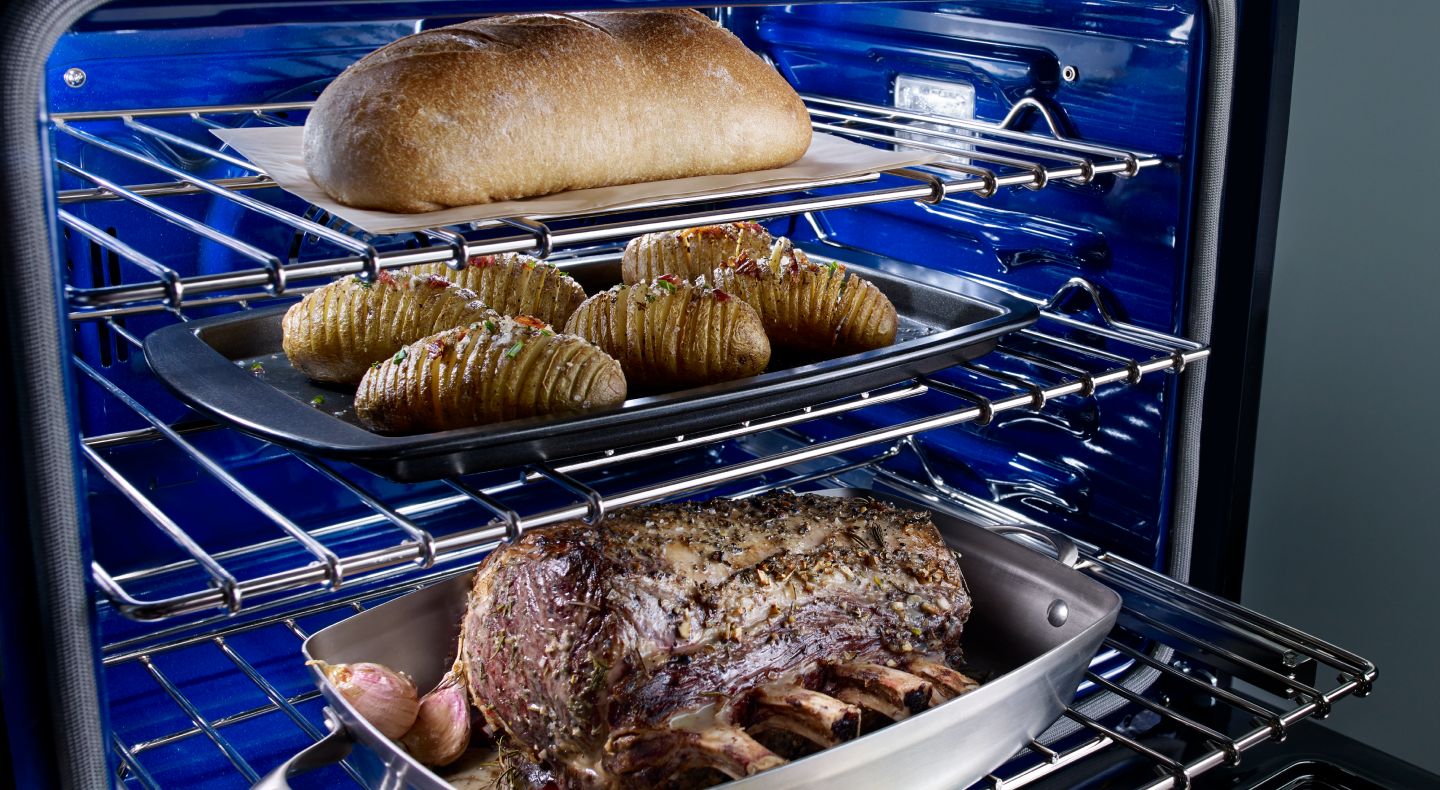 A rack with trays of meat, potatoes and a loaf of bread A rack with trays of meat, potatoes and a loaf of bread