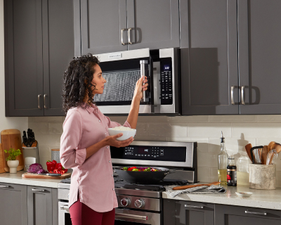 Person opening microwave with bowl in hand