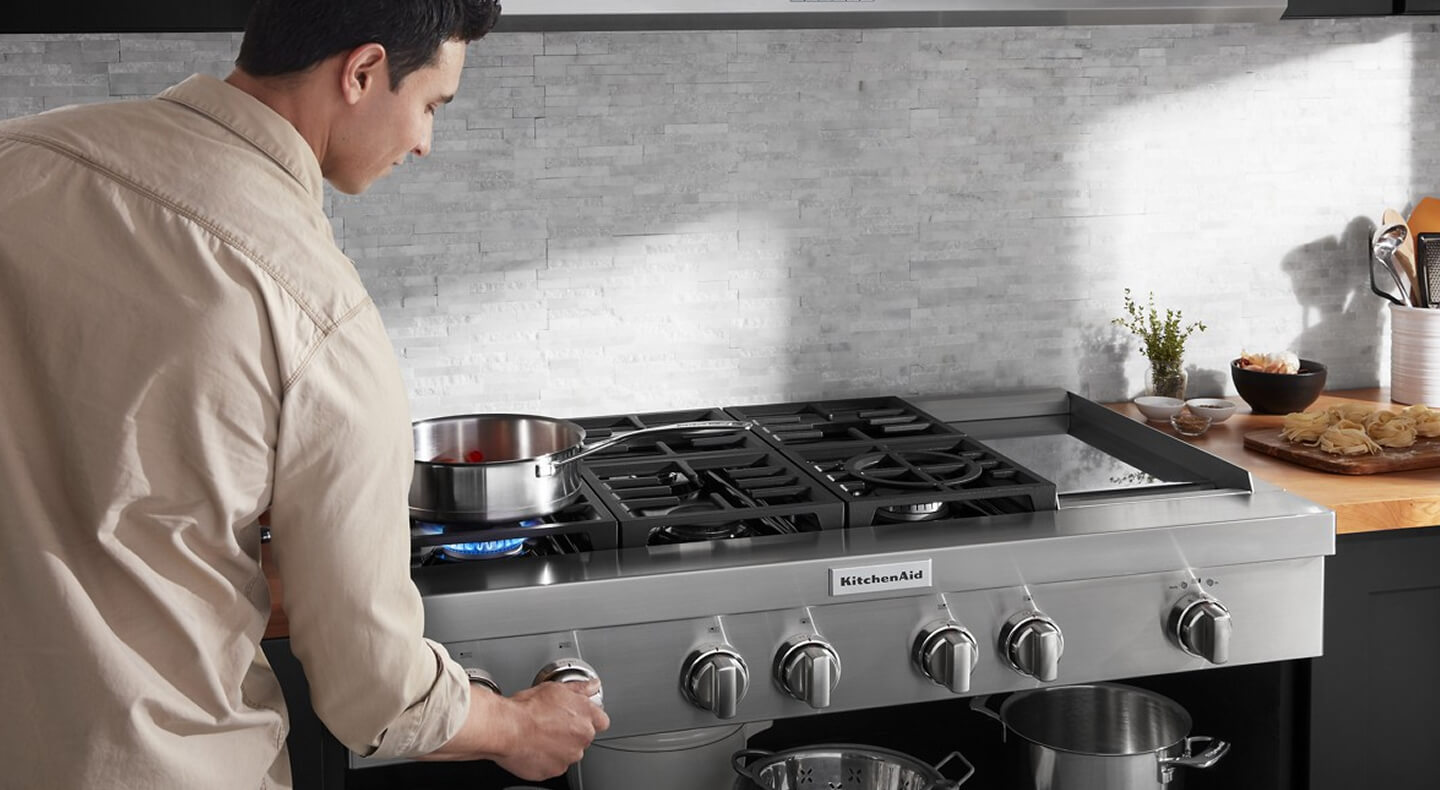 A person cooking on a KitchenAid® cooktop