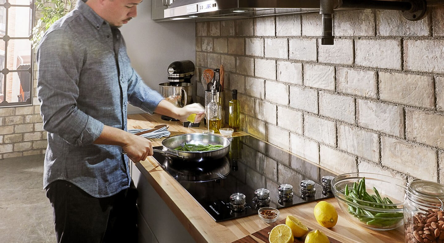 A person cooking on a KitchenAid® electric cooktop A person cooking on a KitchenAid® electric cooktop
