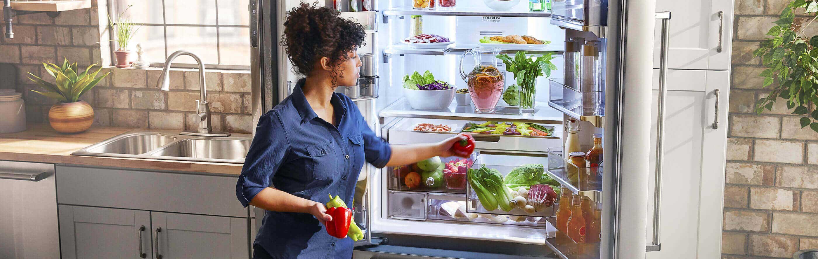 Person loading product into the crisper drawer of a French door refrigerator
