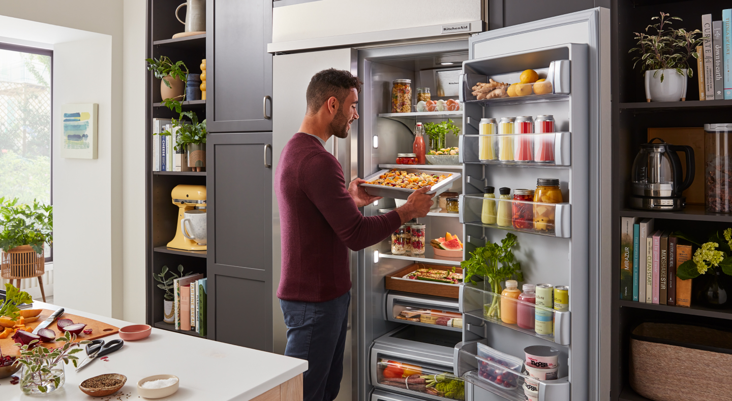 Man removing marinating drawer from refrigerator