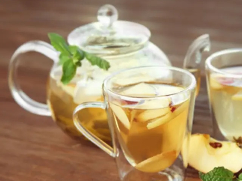 Sliced apples in a clear glass of tea.