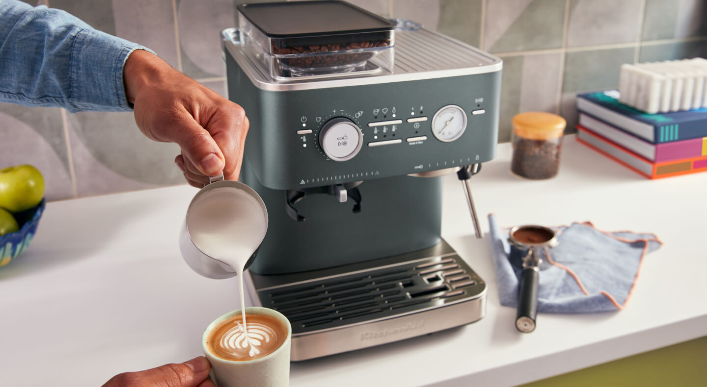 Person creating latte art in front of a KitchenAid® Semi-Automatic Espresso Machine 