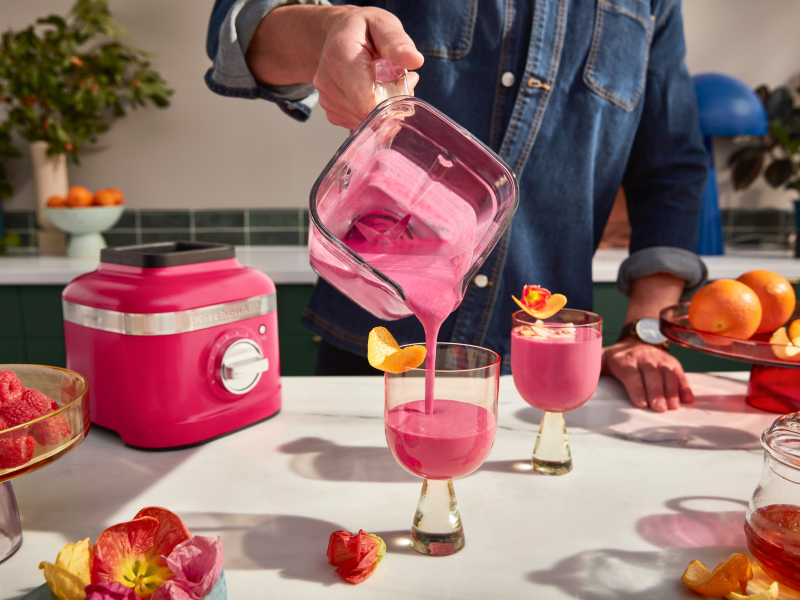 A man pouring a freshly made smoothie from a KitchenAid® blender pitcher into a glass.  A man pouring a freshly made smoothie from a KitchenAid® blender pitcher into a glass.