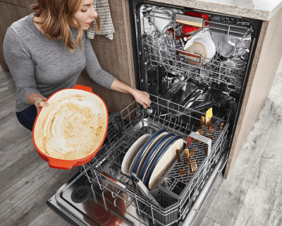 Person kneeling and filling dishwasher bottom rack