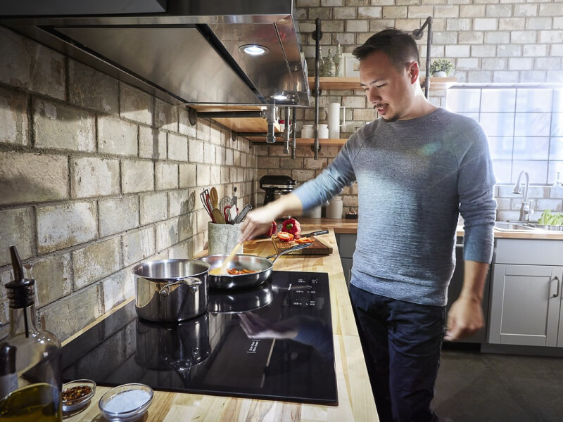 Person sautéing food on a KitchenAid® induction cooktop Person sautéing food on a KitchenAid® induction cooktop