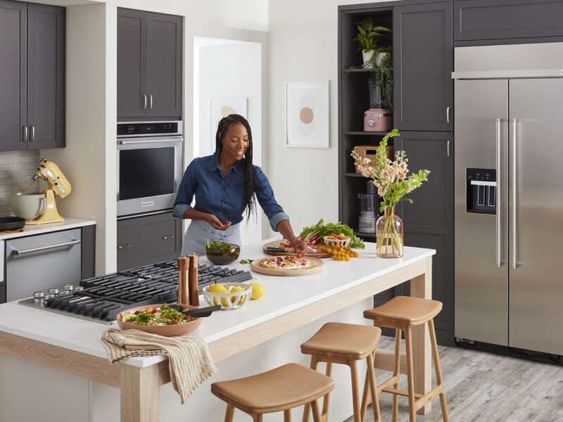 Person garnishing dishes on a kitchen island Person garnishing dishes on a kitchen island