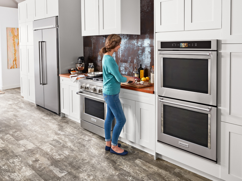 A woman chopping vegetables next to a KitchenAid® double wall oven A woman chopping vegetables next to a KitchenAid® double wall oven