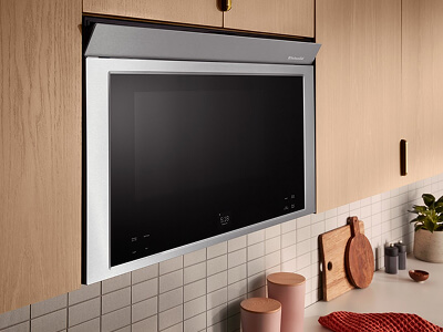 A microwave built in to upper cabinets made from light wood