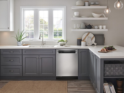 An L-shape kitchen design with gray lower cabinets, white countertops and white shelving and cabinets up top