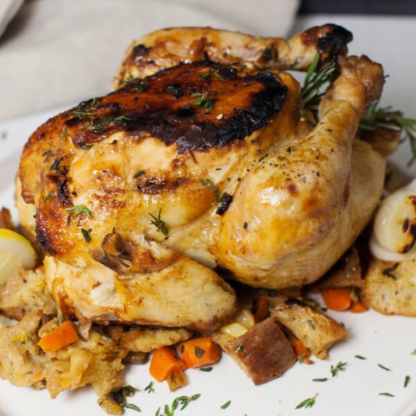 Whole roasted chicken on top of a medley of vegetables