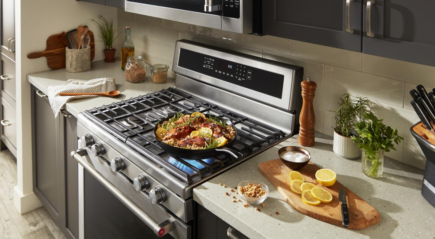 Chicken and grains simmering on a pan on top of a gas range