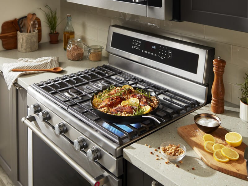 Chicken and grains simmering on a pan on top of a gas range Chicken and grains simmering on a pan on top of a gas range