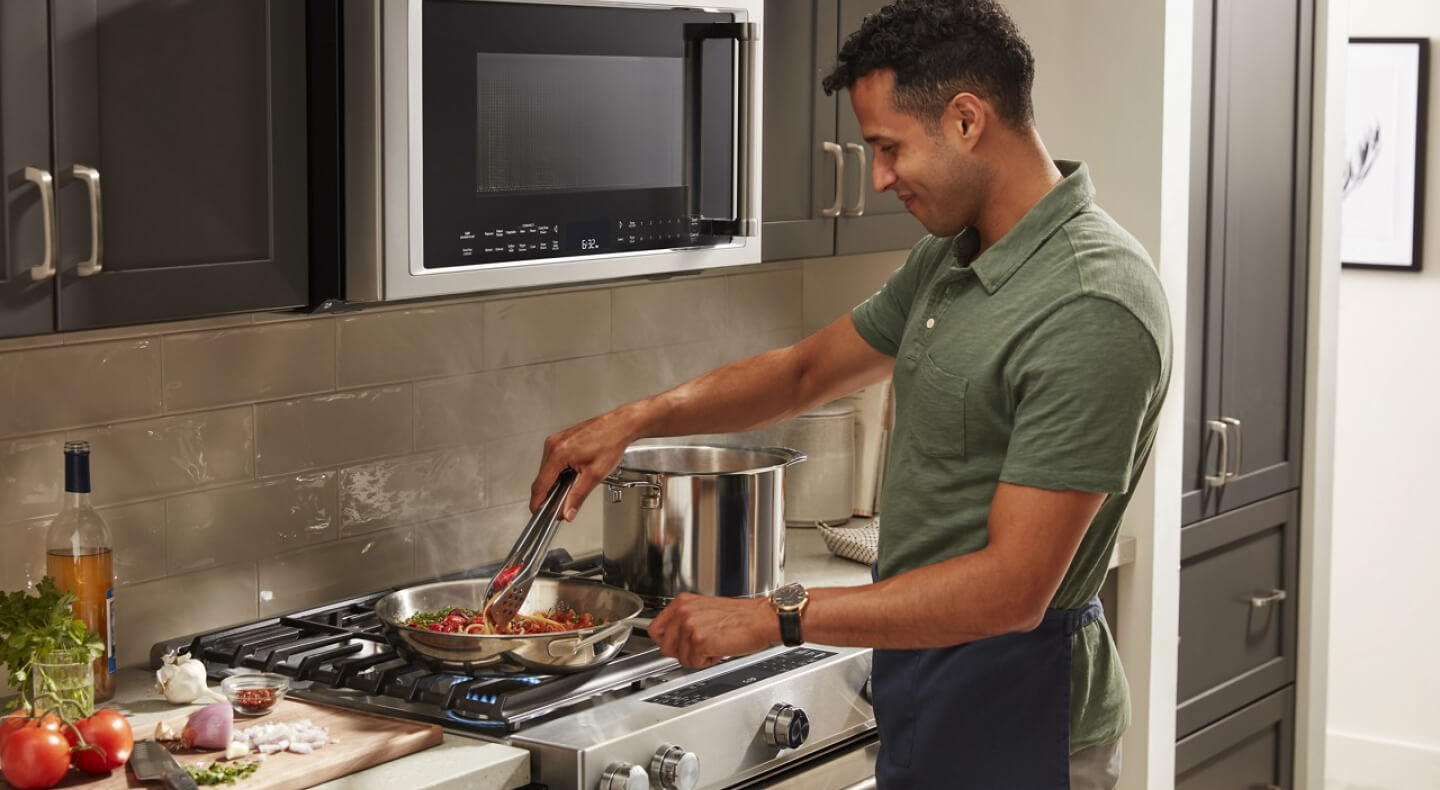 Person stirring a pasta dish on a KitchenAid® stovetop Person stirring a pasta dish on a KitchenAid® stovetop