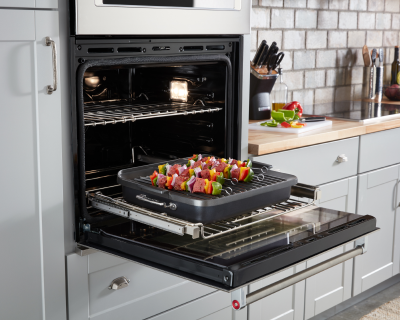 Vegetable kabobs on a grilling pan slid out on a gliding oven rack