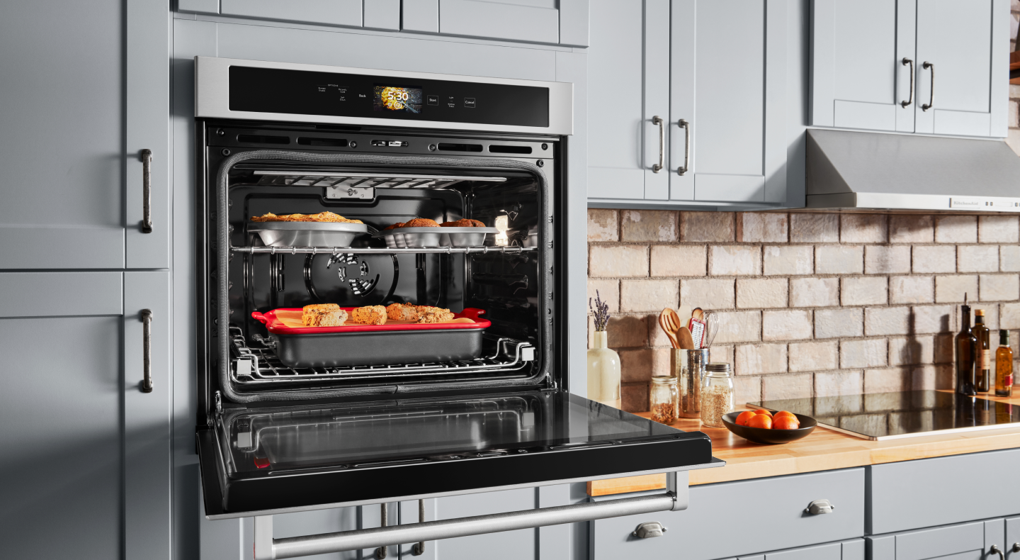 Open, single wall oven with food cooking on the top and bottom racks  Open, single wall oven with food cooking on the top and bottom racks