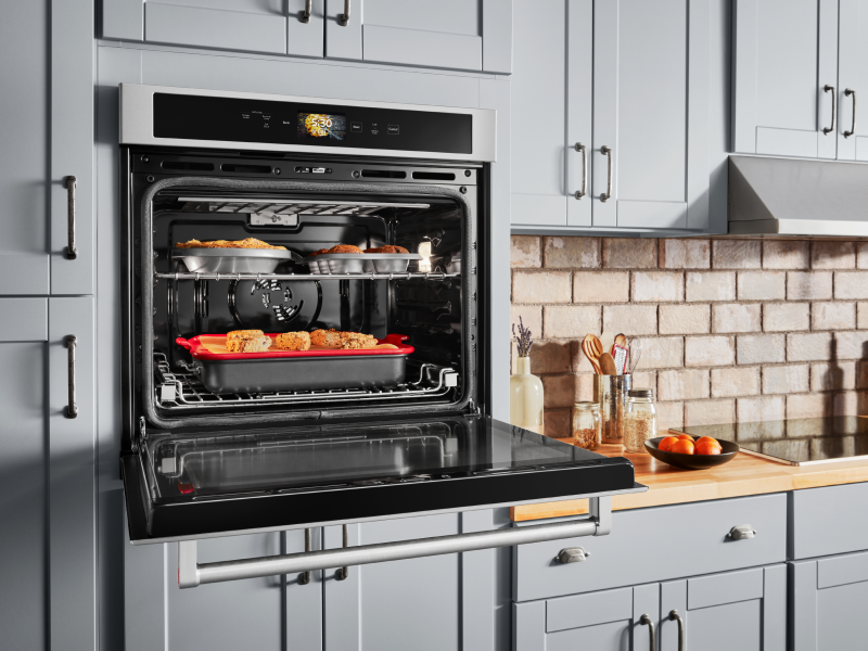 Open, single wall oven with food cooking on the top and bottom racks  Open, single wall oven with food cooking on the top and bottom racks