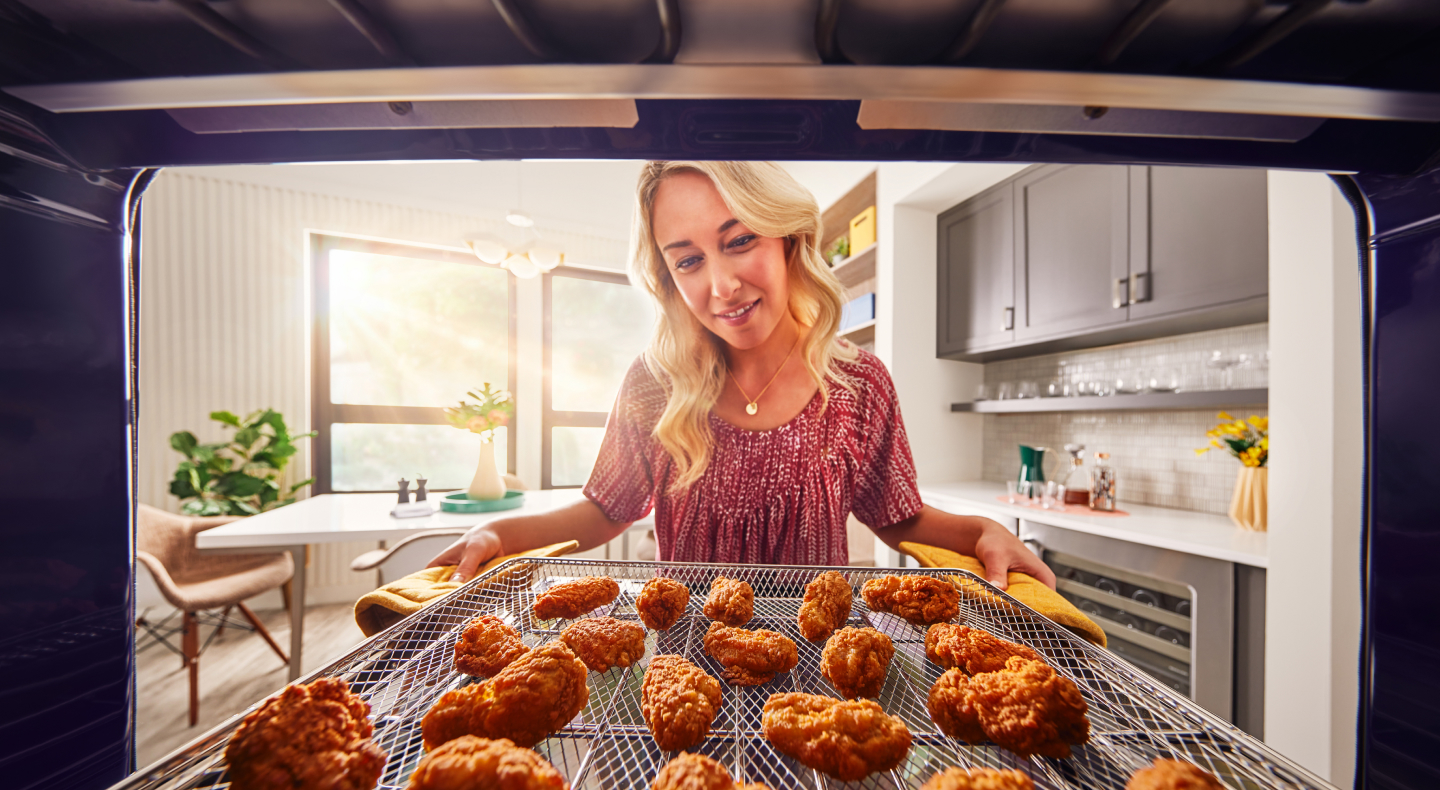 Person pulling out crispy chicken wings from the oven