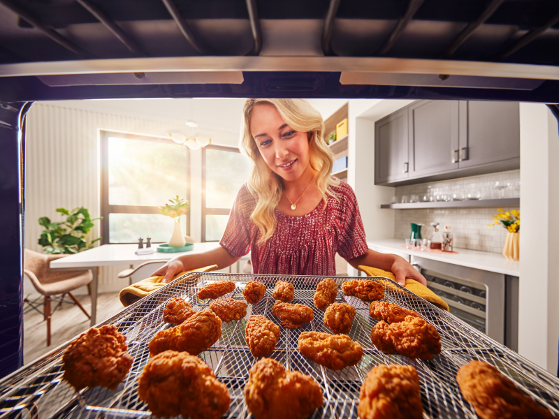 Person pulling out crispy chicken wings from the oven