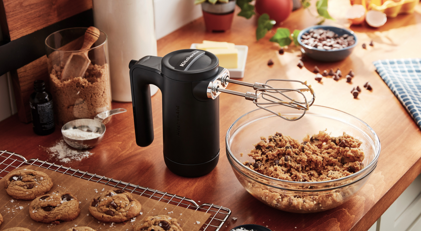 Black KitchenAid® hand mixer with beaters over cookie dough Black KitchenAid® hand mixer with beaters over cookie dough