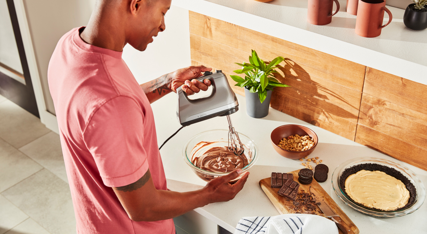 Person using hand mixer with Flex Edge Beaters Person using hand mixer with Flex Edge Beaters