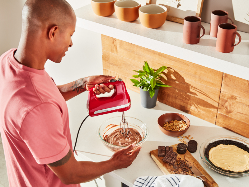 A man using a KitchenAid® hand mixer to make chocolate pie filling. A man using a KitchenAid® hand mixer to make chocolate pie filling.