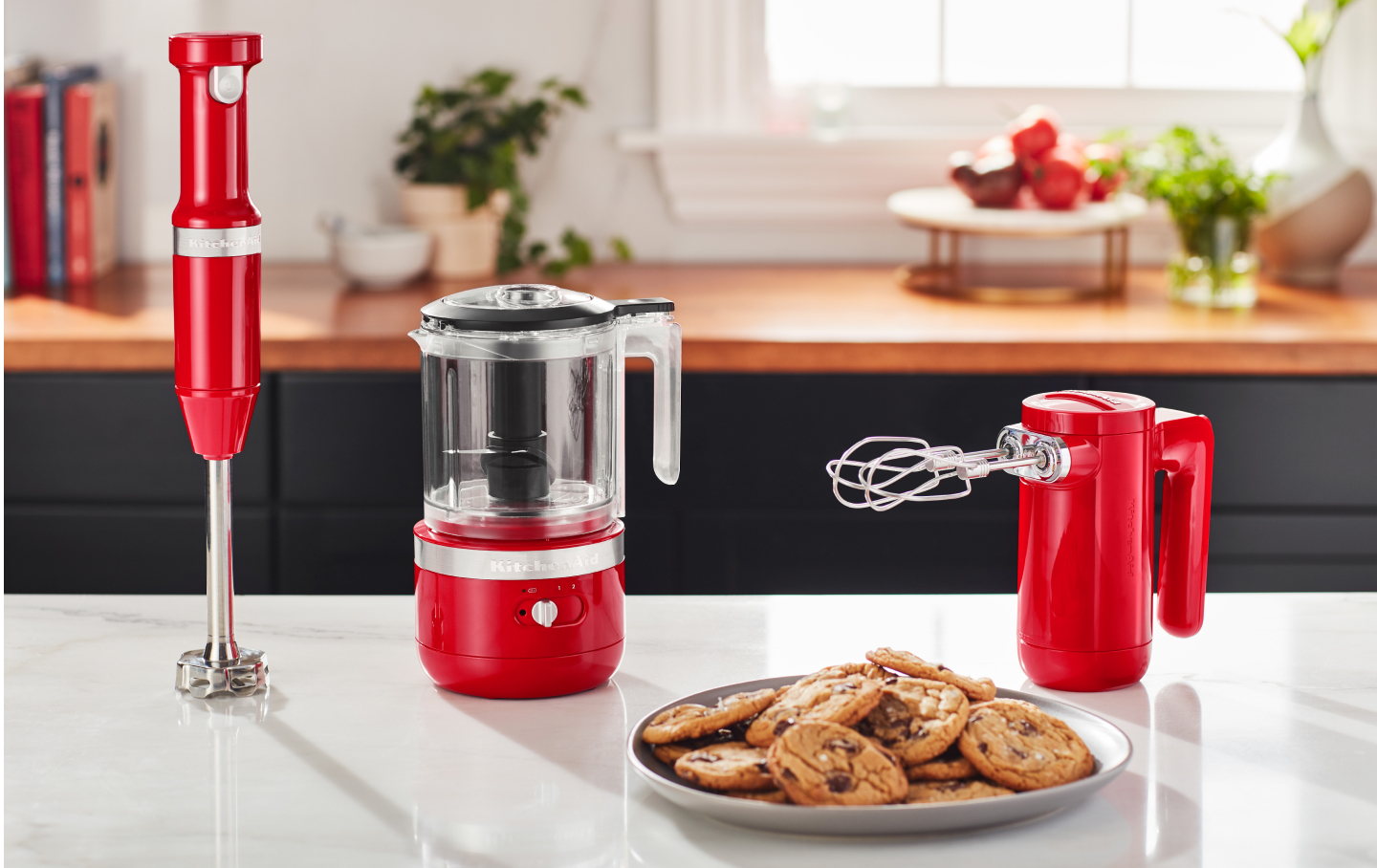 Cordless KitchenAid® hand mixer, hand blender and food chopper next to a plate of freshly baked chocolate chip cookies. Cordless KitchenAid® hand mixer, hand blender and food chopper next to a plate of freshly baked chocolate chip cookies.