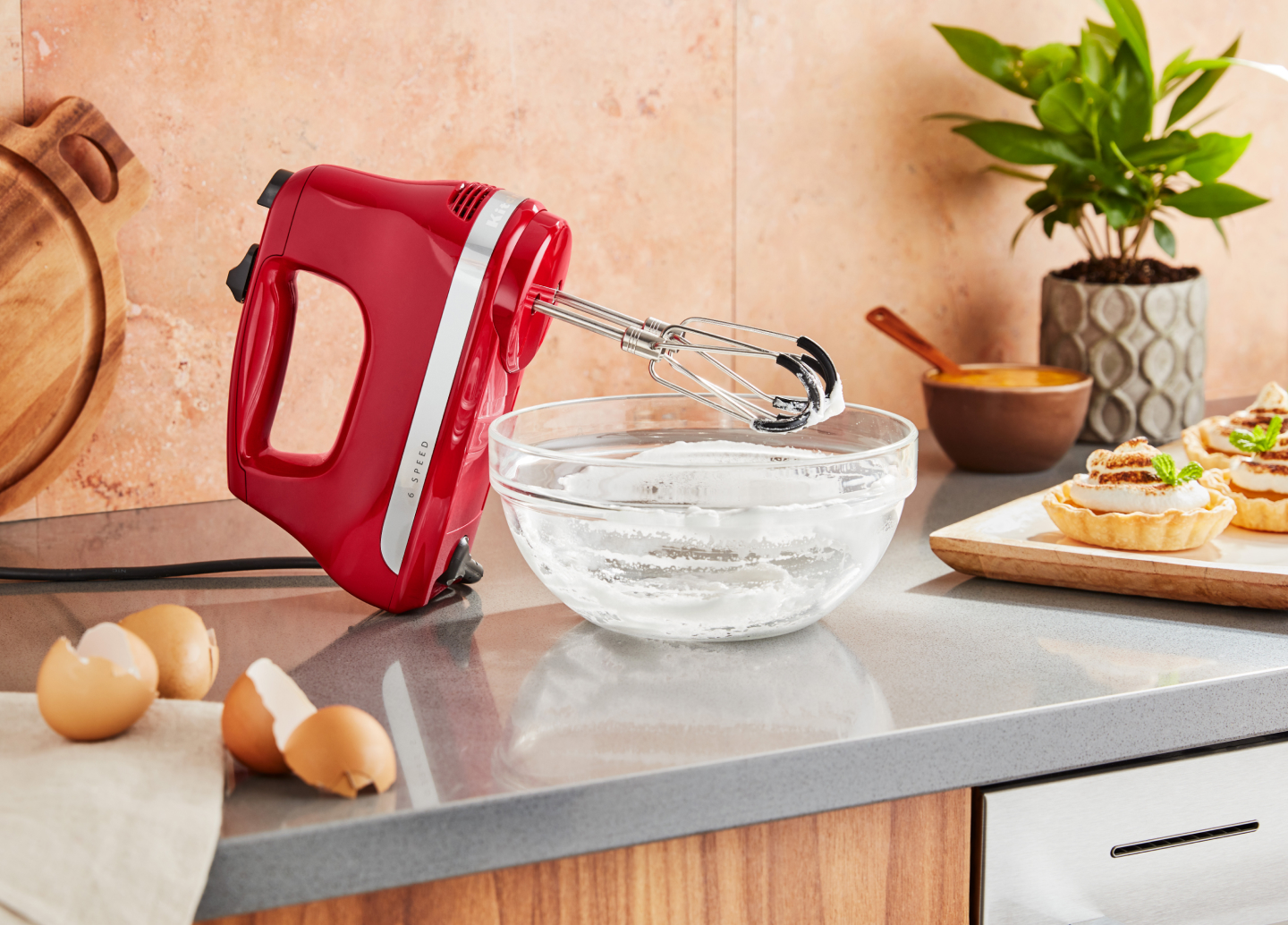 KitchenAid® hand mixer next to an empty mixing bowl of whipped egg whites and meringue tarts. KitchenAid® hand mixer next to an empty mixing bowl of whipped egg whites and meringue tarts.
